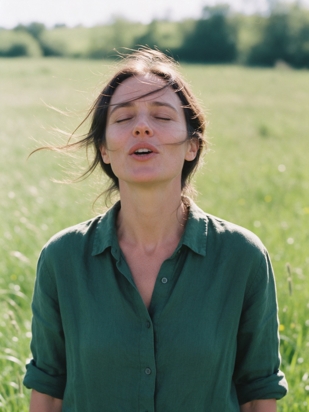 Mulher em um campo, de olhos fechados, falando com naturalidade
